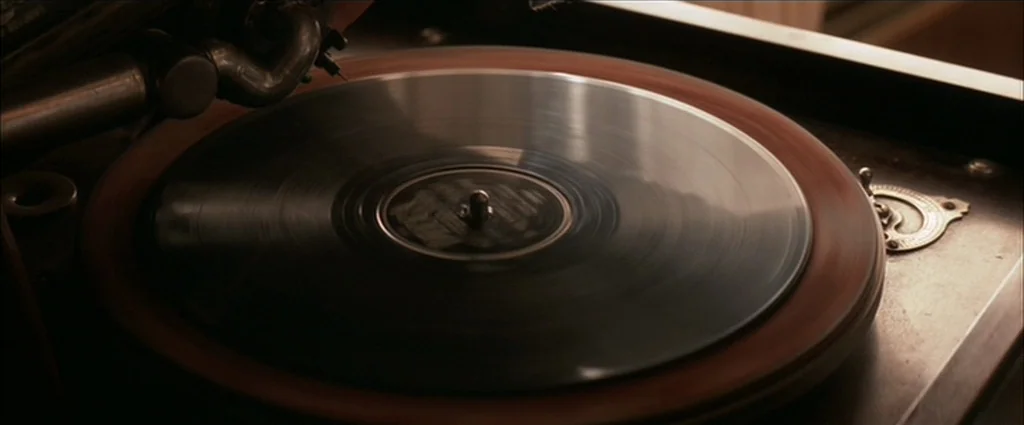 Down In The Valley (2005) movie still: closeup — A close-up view shows a vintage turntable with a rotating vinyl record. The metallic tonearm is…