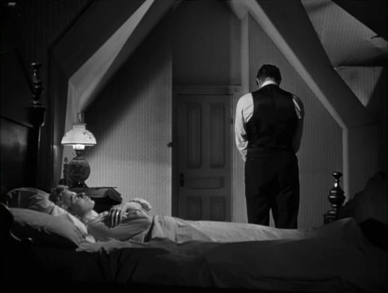 The Night Of The Hunter (1955) movie still: wide — An attic-style room with sloping ceilings and wallpaper has a bed and door. A woman rests in bed…