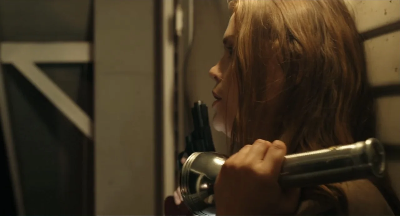 Ted Bundy: American Boogeyman (2021) movie still: closeup — A dimly lit indoor corridor with textured walls features a young woman standing…