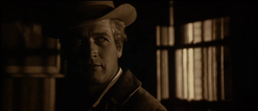 Butch Cassidy and the Sundance Kid (1969) movie still: medium — A dimly lit cabin interior features a window with slatted blinds. A man wearing a…