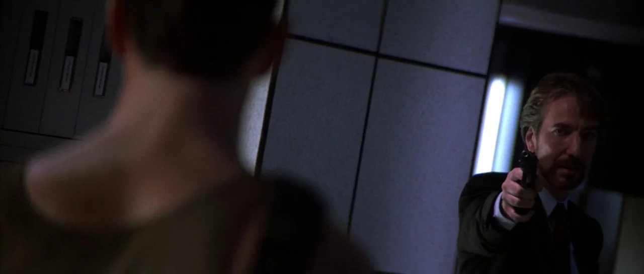 Die Hard (1988) movie still: medium — A dark corporate office features wall-mounted filing binders near a bright light source. A man in a suit…