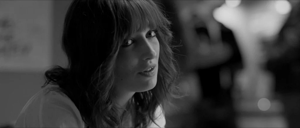Control movie still: closeup — An interior space features soft out-of-focus highlights in the blurred background. A young woman turns to look at the…
