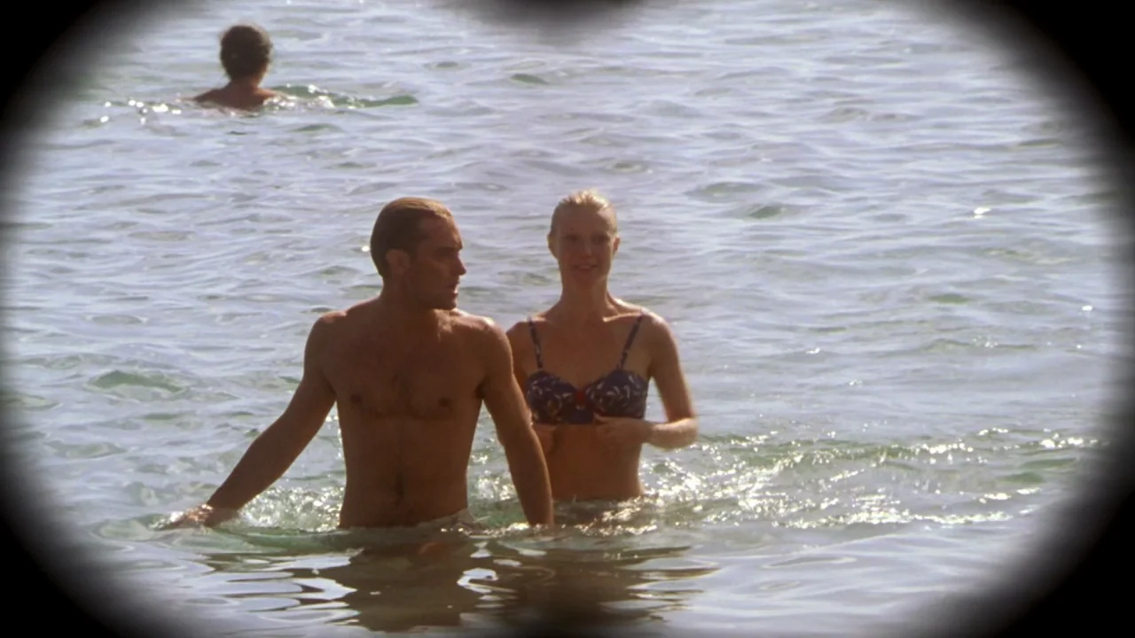 The Talented Mr. Ripley (1999) movie still: medium — A man and woman wade through shallow water with an ocean backdrop. The camera view is framed by…