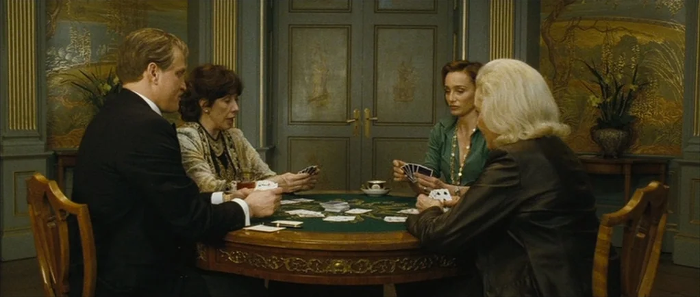 The Walker (2007) movie still: medium — A formal room features decorative chinoiserie-style wallpaper and double doors in the background. Four…