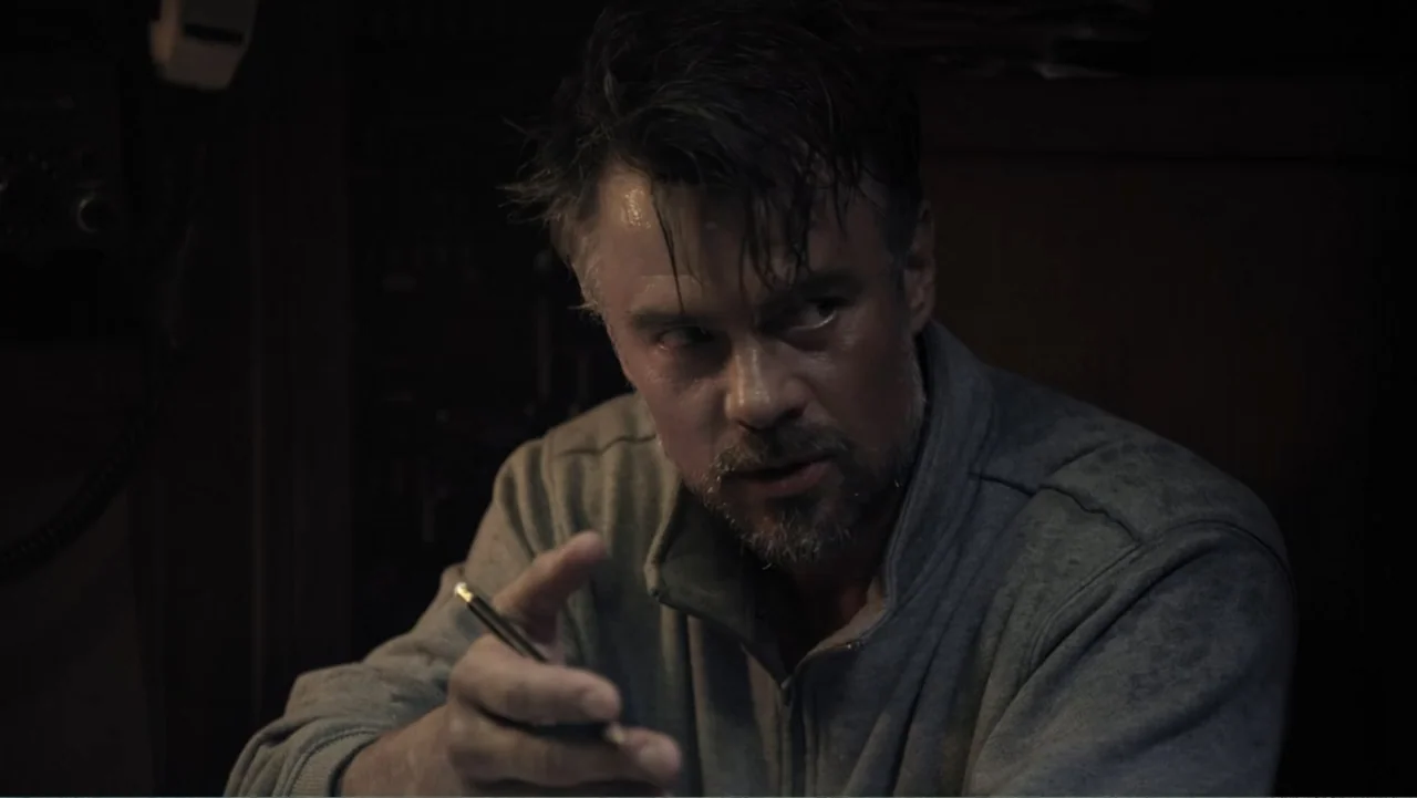 Capsized: Blood in the Water (2019) movie still: medium — A dark, cramped interior space with minimal architectural detail visible. A middle-aged…