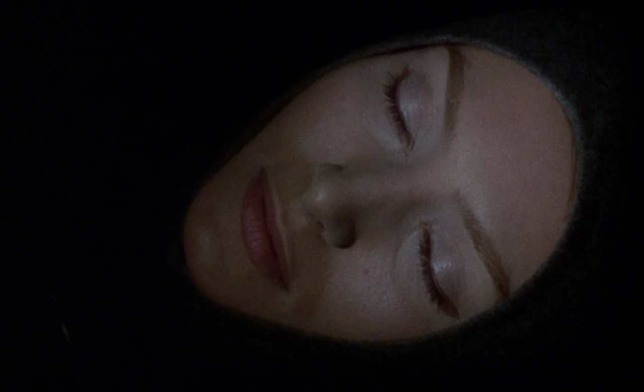 Blanche (1971) movie still: closeup — A close-up view of a woman's face emerging from a deep black background. The woman rests with her eyes shut…