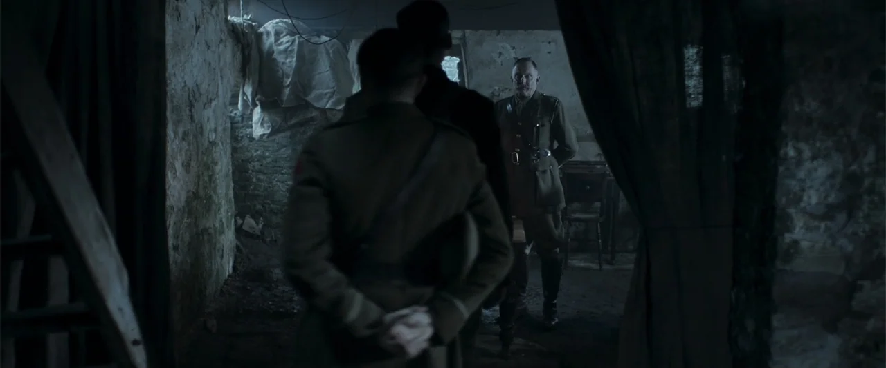 Gone Missing -  Old John's Final Journey (2014) movie still: medium — A dark stone room contains a wooden chair and a dimly lit corner. A uniformed…