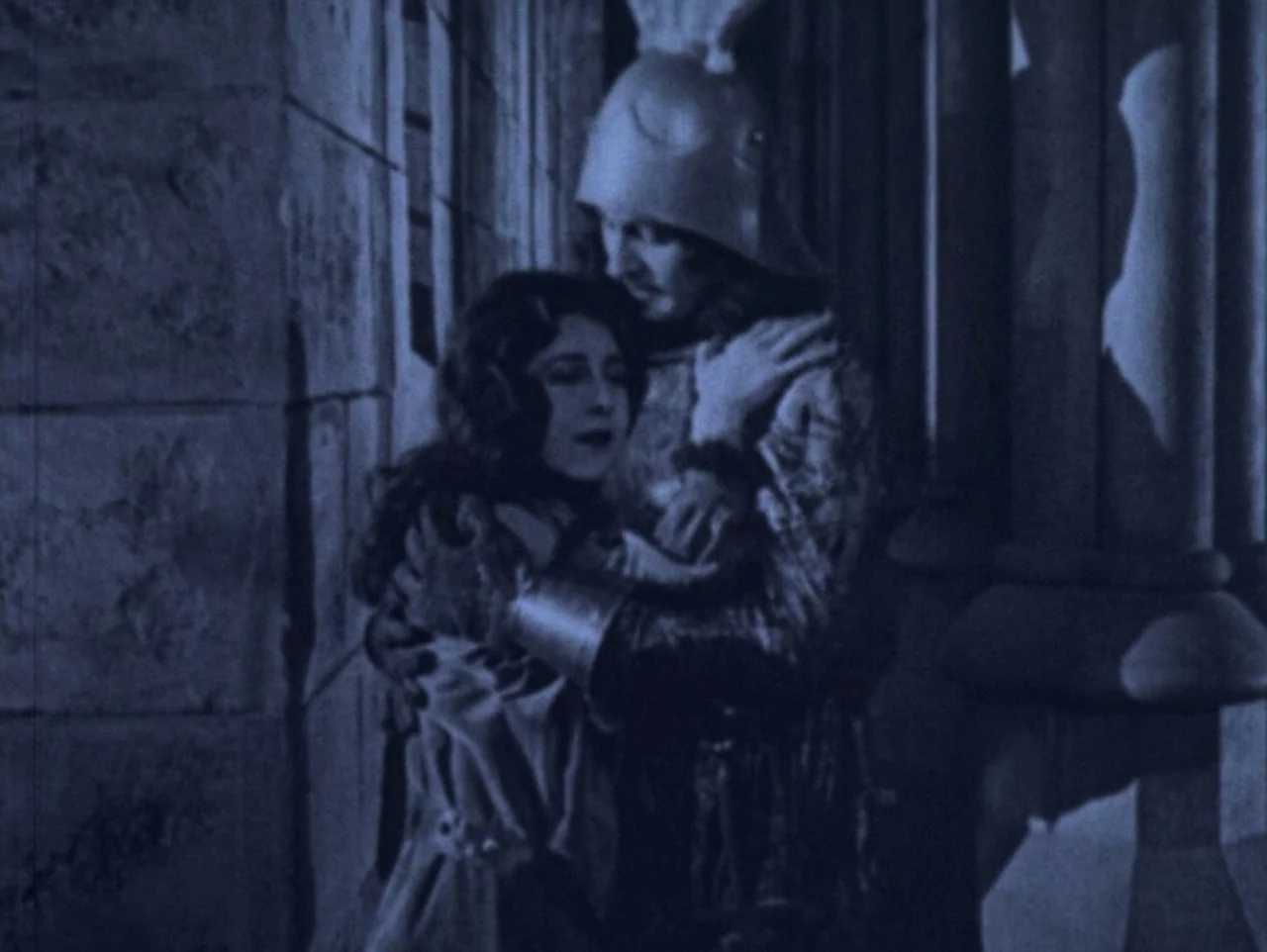 The Hunchback of Notre Dame (1923) movie still: medium — A stone corridor with large vertical columns and shadows cast against the masonry. A woman…