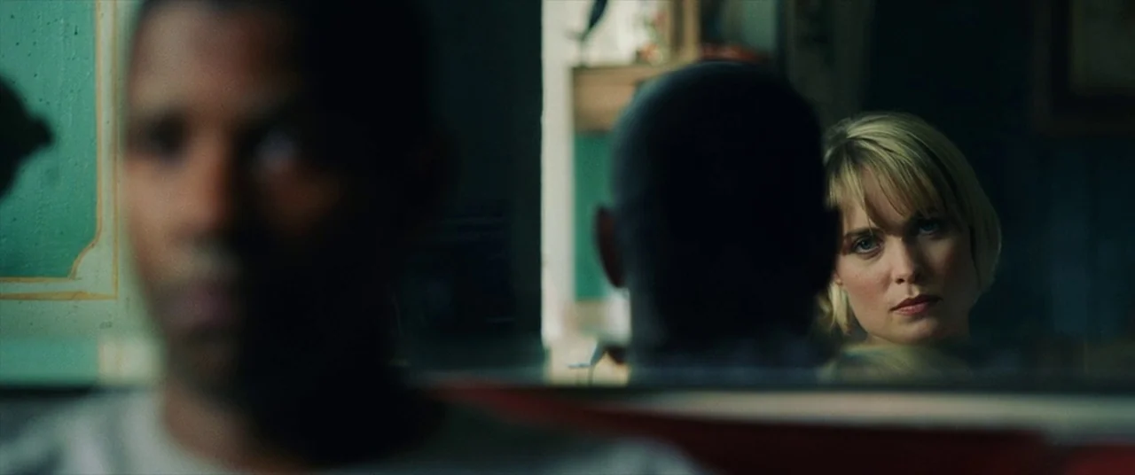 Man on Fire (2004) movie still: medium — A dimly lit restaurant booth features teal wall panels and red upholstery. A man in the foreground is…