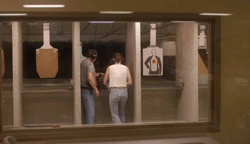 Kate Plays Christine (2016) movie still: wide — An indoor shooting range consists of concrete dividers separating individual lanes with paper…