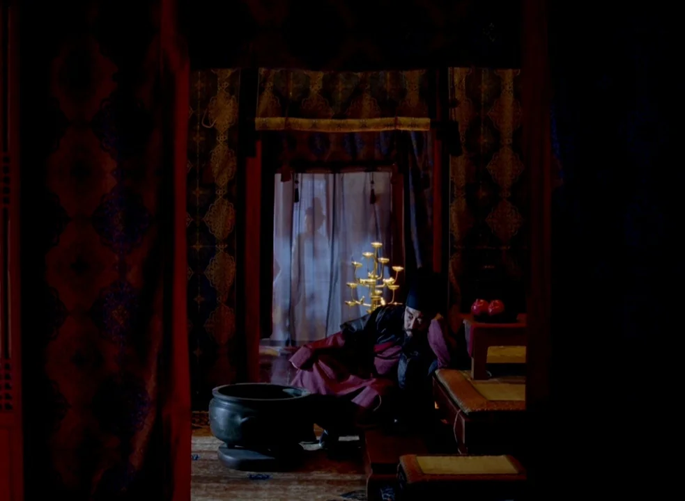The Assassin (2015) movie still: medium — An interior space features patterned dark textiles and a low wooden platform for seating. A man in…