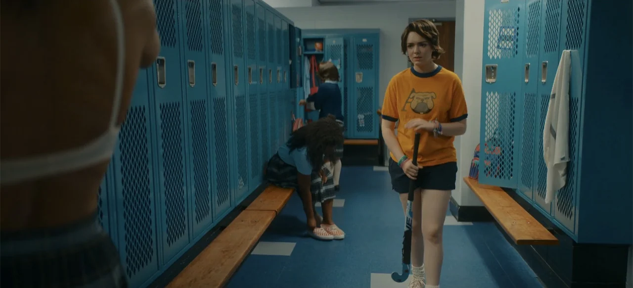 My Best Friend's Exorcism (2022) movie still: medium — A school locker room features rows of blue metal lockers and wooden benches. A teenage girl…