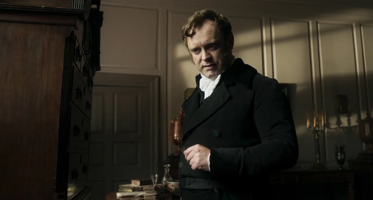 Peterloo (2018) movie still: medium — A wood-paneled room features period furniture including a large cabinet and a desk. The man stands near the…