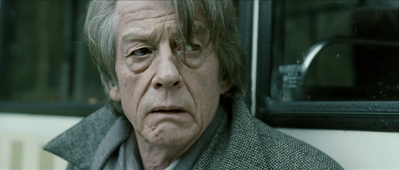 The Oxford Murders (2008) movie still: closeup — An interior of a public bus shows a window with dark framing and glass. An elderly man with grey…
