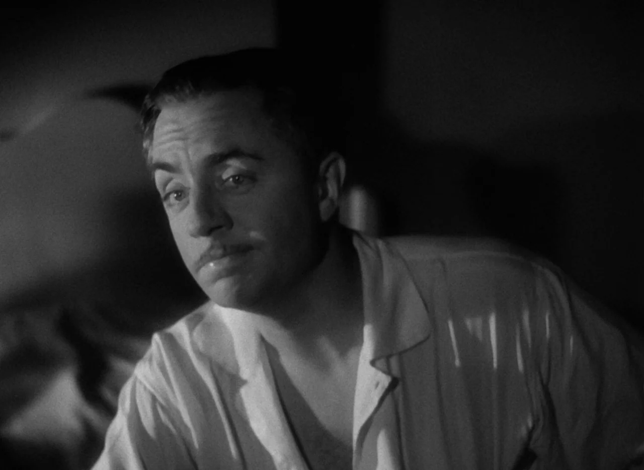 The Thin Man (1934) movie still: closeup — A dimly lit room with the subject in the foreground illuminated by low-key lighting. The man wears a…