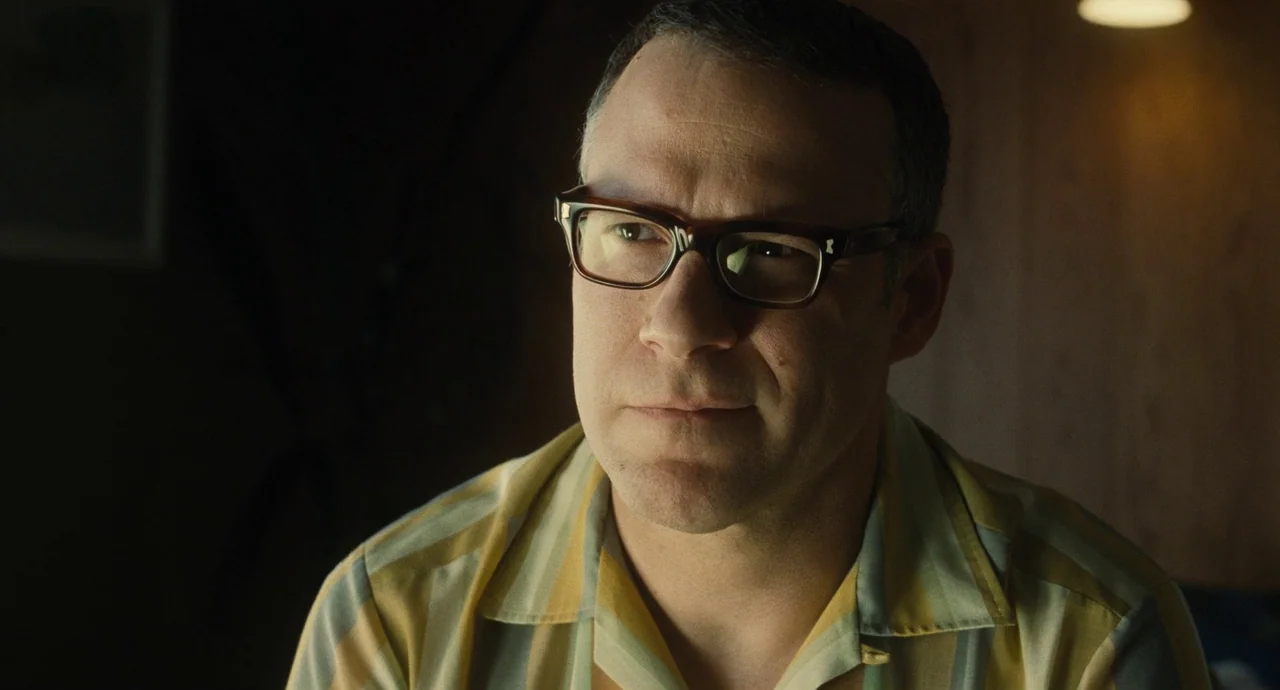 The Fabelmans (2022) movie still: closeup — A man stands in a dimly lit room with dark wood paneling. He looks slightly off-camera while wearing a…