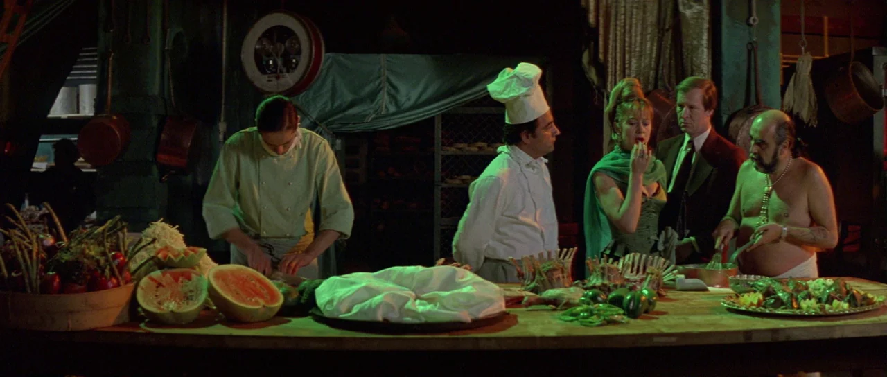 The Cook, The Thief, His Wife & Her Lover (1989) movie still: wide — A dimly lit industrial food preparation area filled with fresh produce and…