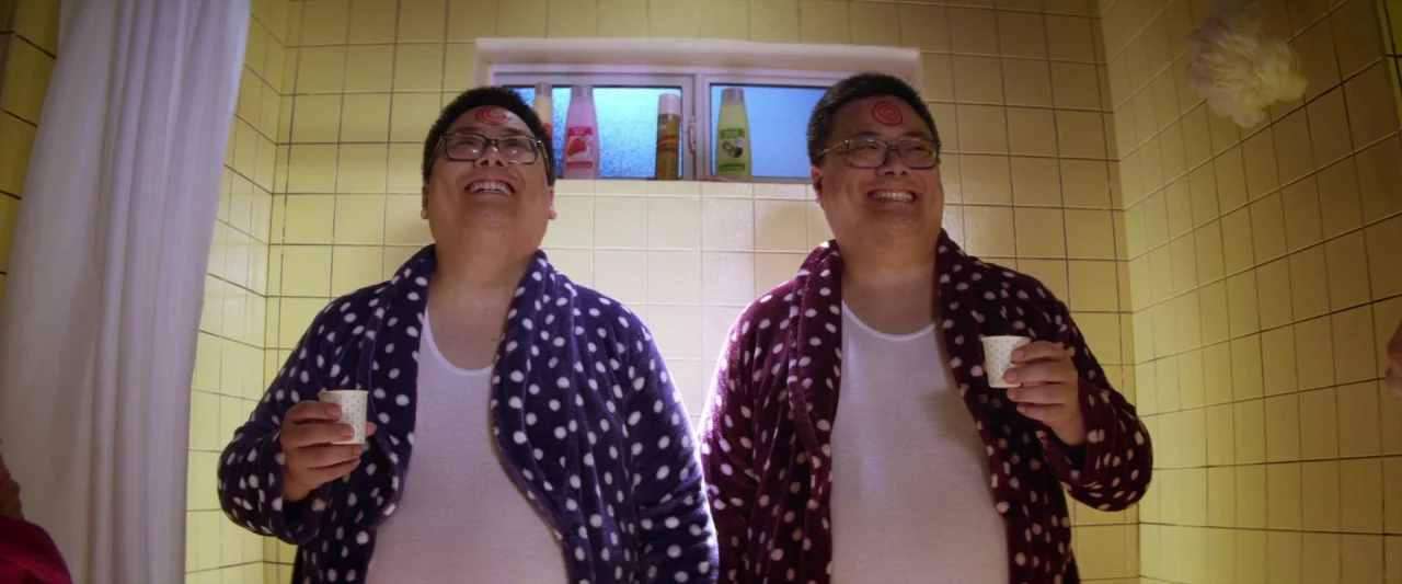 Seven Stages to Achieve Eternal Bliss (2018) movie still: medium — A tiled bathroom shower area features yellow square tiles and a small rectangular…