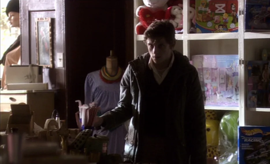 Dear Wendy (2005) movie still: medium — A cluttered retail space filled with shelves of toys and assorted vintage goods. A young man stands in the…