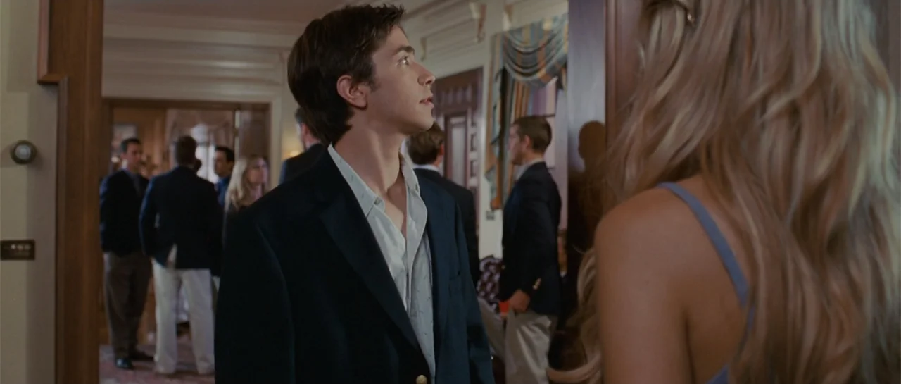 Accepted (2006) movie still: medium — A residential hallway filled with guests dressed in formal attire during a social gathering. A young man…