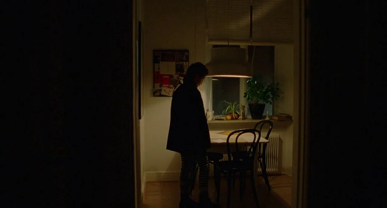 We Are The Best! (2013) movie still: wide — A dimly lit room features a small dining table illuminated by an overhead pendant light. A young person…