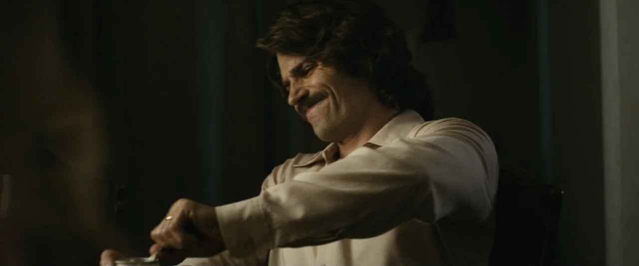 The Case for Christ (2017) movie still: medium — A dimly lit room with muted wall tones and sparse decor. A man sits at a table and stirs the…