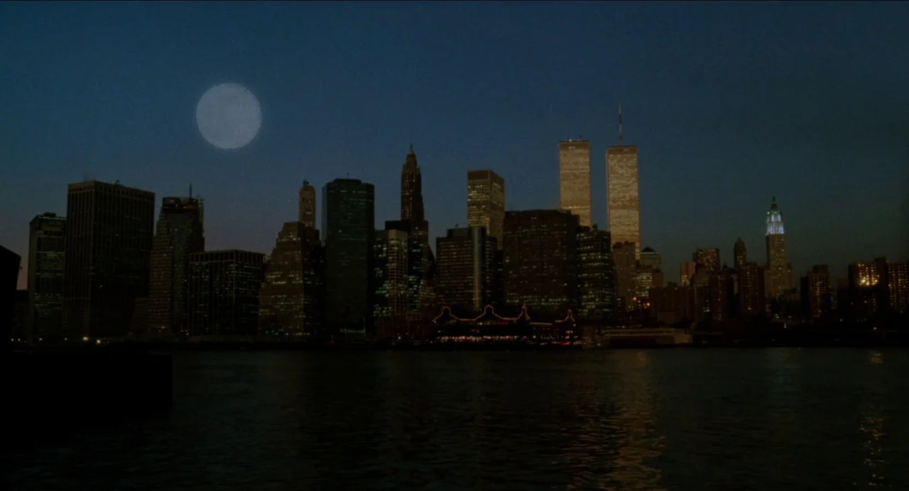 Moonstruck (1987) movie still: establishing — The New York City skyline at night features the illuminated Twin Towers of the WTC. A large full moon…