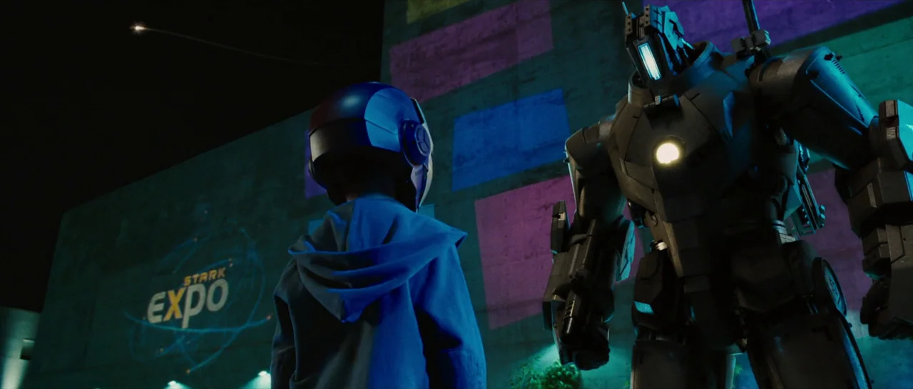 Iron Man 2 (2010) movie still: medium — A night setting outdoors at the Stark Expo with a large concrete structure wall. A child stands before a…