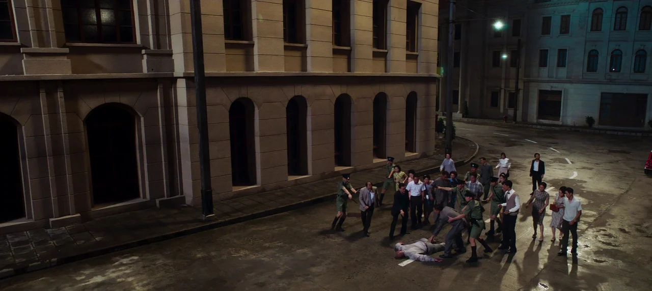 Master Z: The Ip Man Legacy (2018) movie still: wide — A nighttime street corner features a large tan building with arched ground-level windows. A…