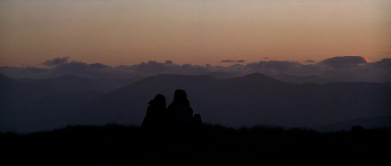 Braveheart (1995) movie still: wide — A mountain ridge sits in darkness beneath a wide twilight sky with distant rolling peaks. Two figures sit…