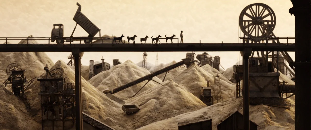 Isle of Dogs (2018) movie still: wide — A vast industrial landscape of dirt mounds, mining equipment, and conveyor belts extends below. A child…