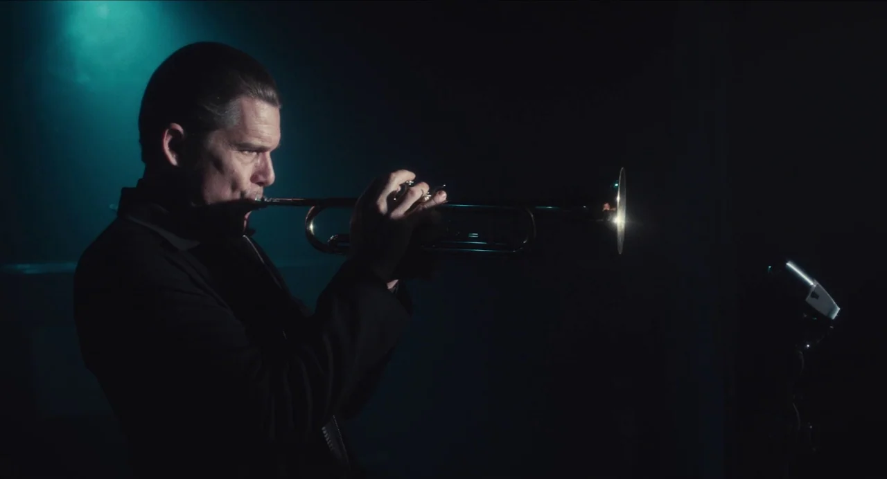 Born To Be Blue (2015) movie still: medium — A dark, minimalist performance space with a single blue light source from above. A man plays the…