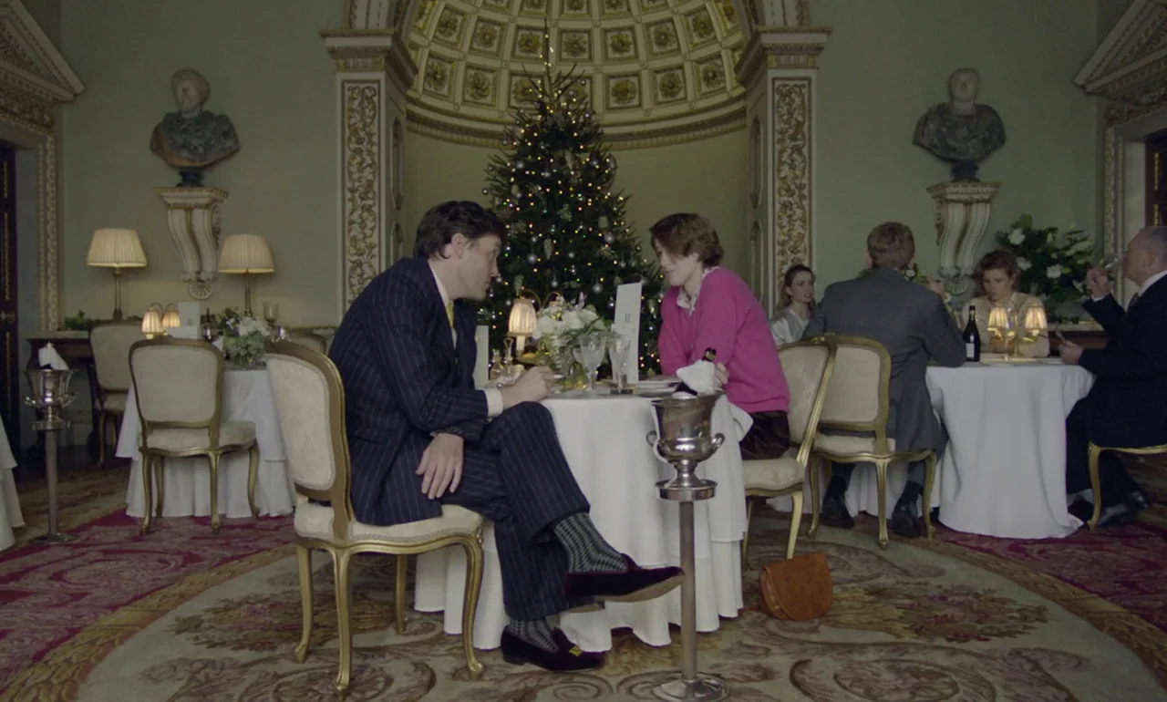 The Souvenir (2019) movie still: fullbody — An opulent, classic room with a large Christmas tree placed in a central alcove. A man and a woman sit…