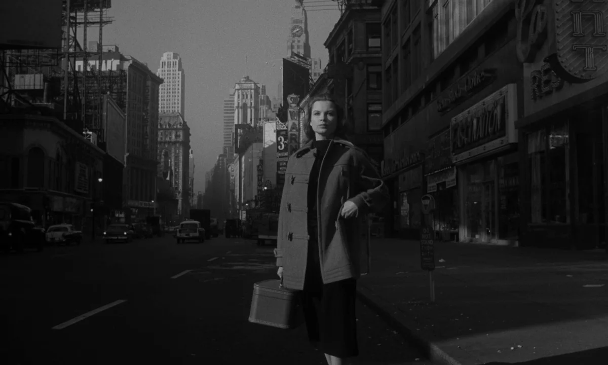 Sweet Smell of Success (1957) movie still: medium — A desolate 1950s New York City street lined with tall buildings and signs. A woman stands in the…