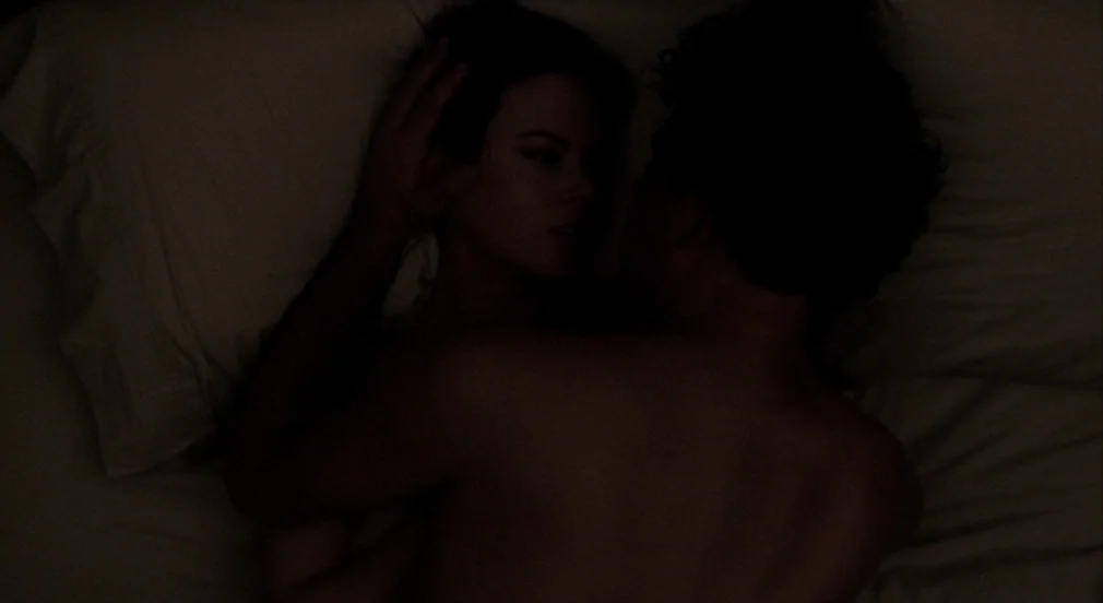 Birth (2004) movie still: medium — A dark, dimly lit bed with rumpled white linens at night. A couple rests in each other's arms in the shadows.