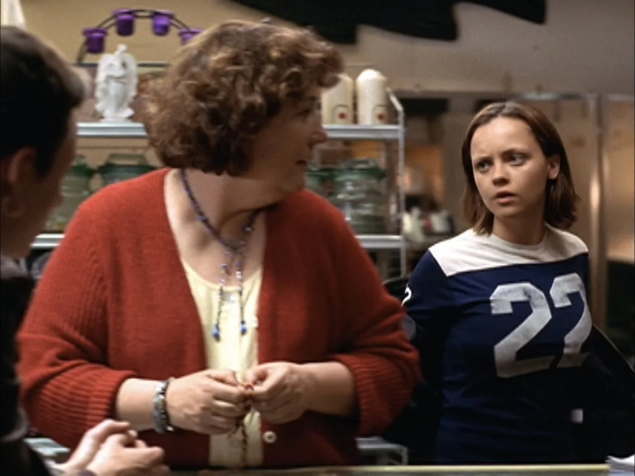 The Laramie Project (2020) movie still: medium — Two women interact across a service counter inside a cluttered retail space. The older woman…