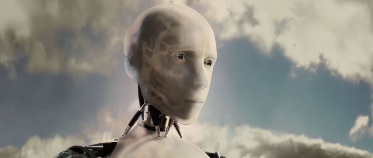 I, Robot (2004) movie still: closeup — A white humanoid robot head stands against a backdrop of overcast, grey clouds. The mechanical figure tilts…