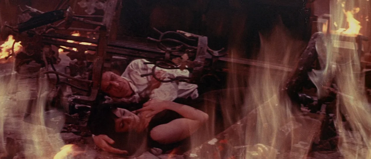 The Tomb of Ligeia (1964) movie still: medium — A room engulfed in flames contains scattered debris and fallen architectural remains. A man and a…