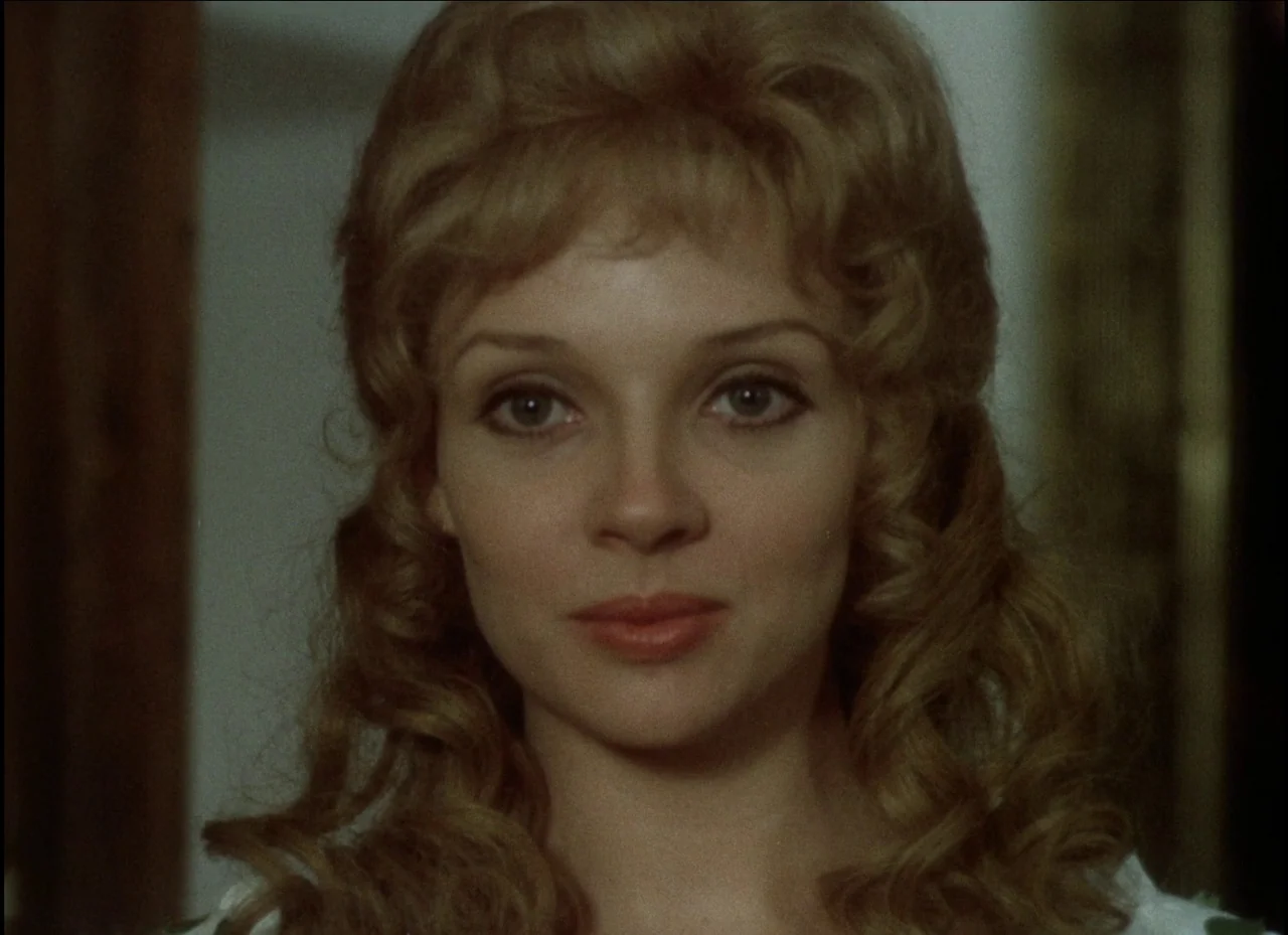 Beauty and the Beast (1979) movie still: closeup — A head-and-shoulders portrait of a woman inside a sparsely lit, indistinct room. The woman looks…