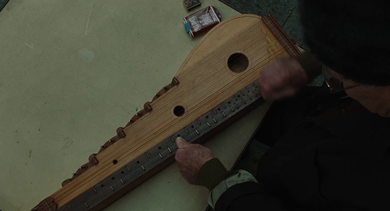 Doubt (2008) movie still: medium — A wooden table surface features a stringed instrument and a pack of cigarettes. An elderly man with weathered…