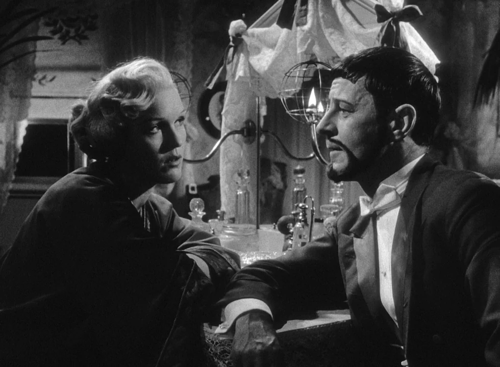Smiles Of A Summer Night (1955) movie still: medium — A dimly lit room features a vanity table cluttered with glass bottles and jars. A man in…