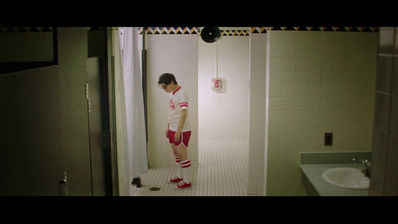 Collective: Unconscious (2016) movie still: fullbody — A locker room with white square tiles and a decorative patterned border near ceiling. A…