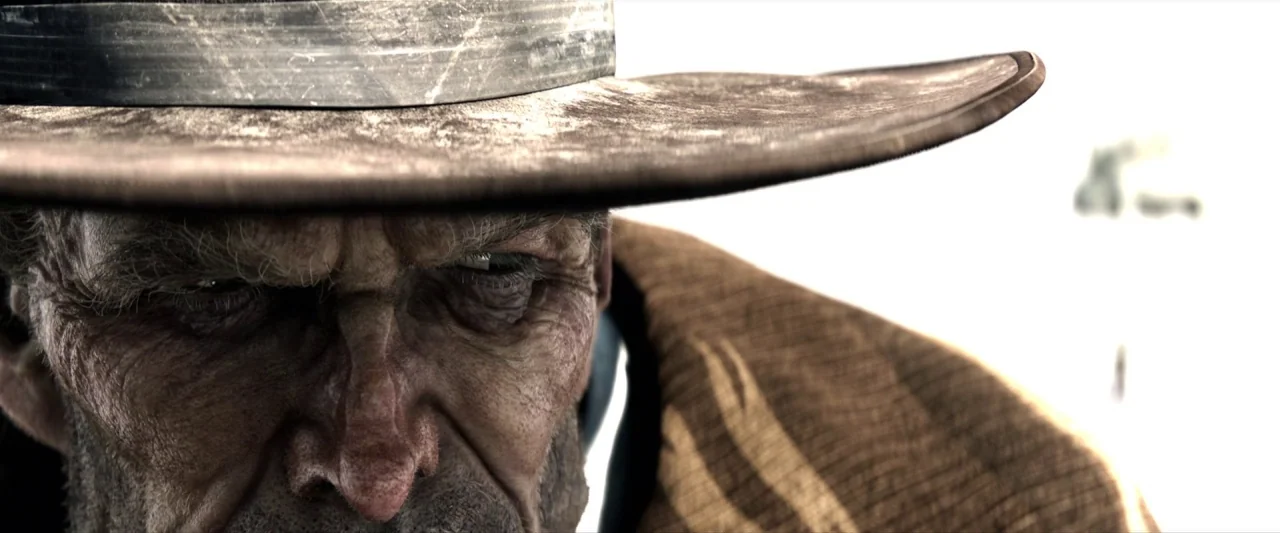 Rango (2011) movie still: closeup — An extremely close-up view of an elderly man wearing a wide-brimmed hat. He gazes downward with a weathered face…