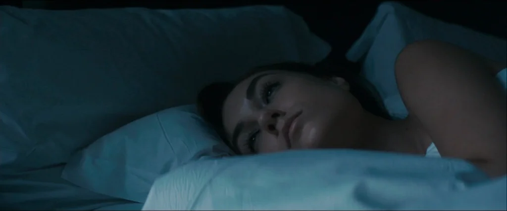 The Girlfriend Experience (2009) movie still: closeup — A person lies on a soft pillow in a darkened environment. They are resting their head while…