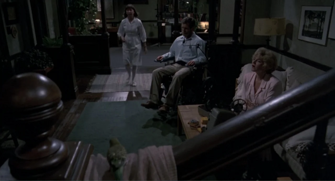 An Experiment in Fear: The Making of Monkey Shines (2014) movie still: medium — A dimly lit room features a wheelchair user, a standing woman, and a…