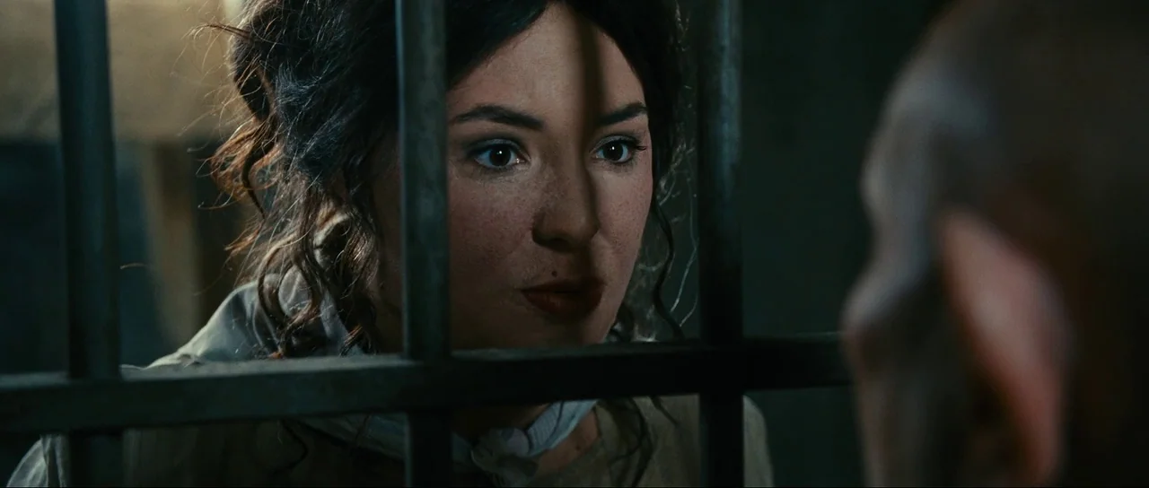 The Extraordinary Adventures of Adèle Blanc-Sec (2010) movie still: closeup — A dimly lit stone environment enclosed by thick vertical iron bars. A…