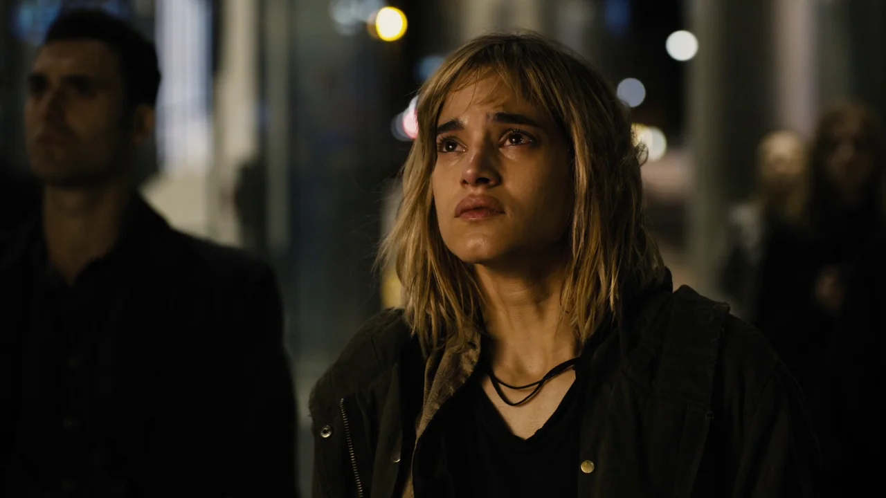 Fahrenheit 451 (2018) (2018) movie still: medium — A dark, out-of-focus city street serves as the backdrop for two people at night. The woman looks…