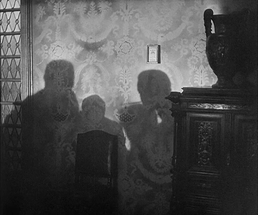 M (1931) movie still: medium — A dark indoor space features ornate patterned wallpaper and an antique dark wooden sideboard. Three large human…