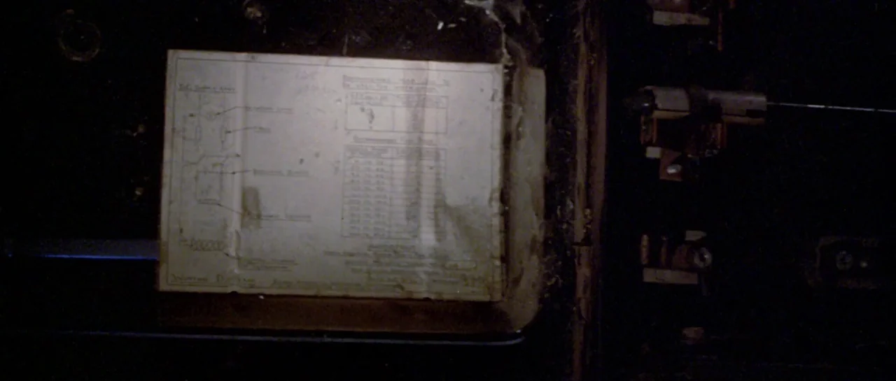 Friday the 13th Part III (1982) movie still: closeup — An electrical panel interior features a worn, cream-colored paper schematic taped to the…