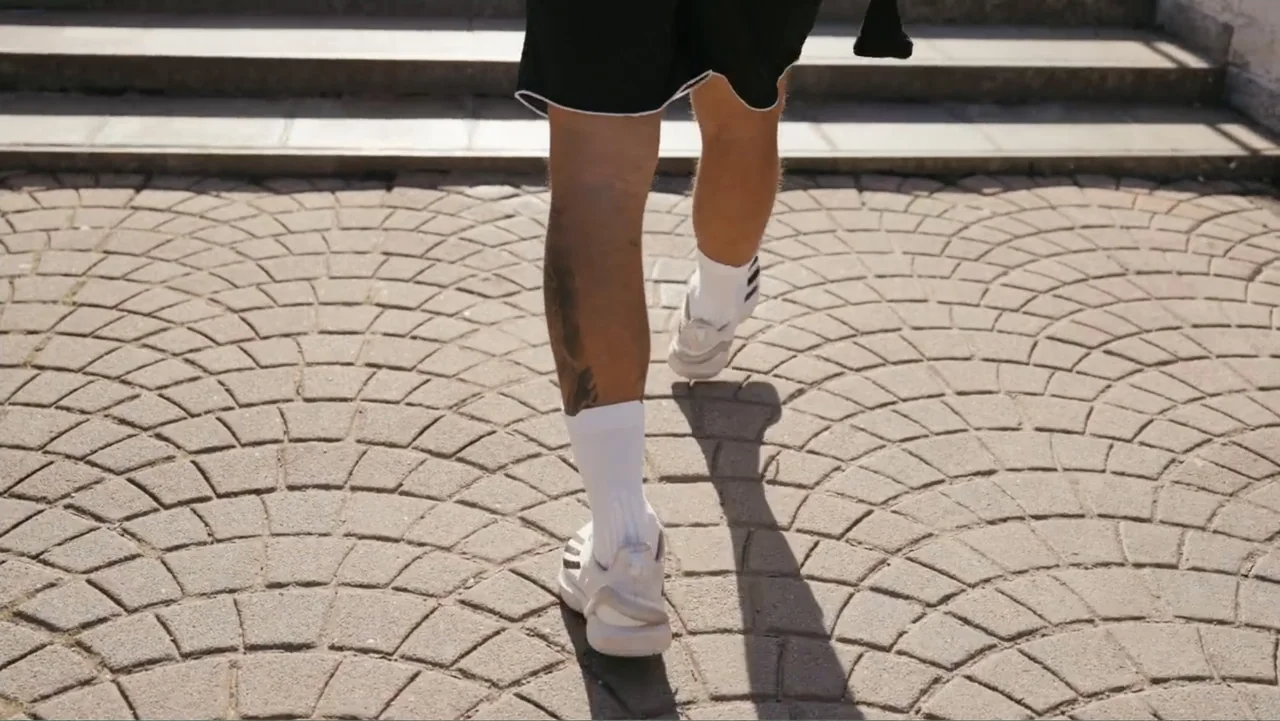 FRAGILE - The story of Nicolò Fagioli (2024) movie still: fullbody — A stone paved area with a raised concrete step in the background. A person in…
